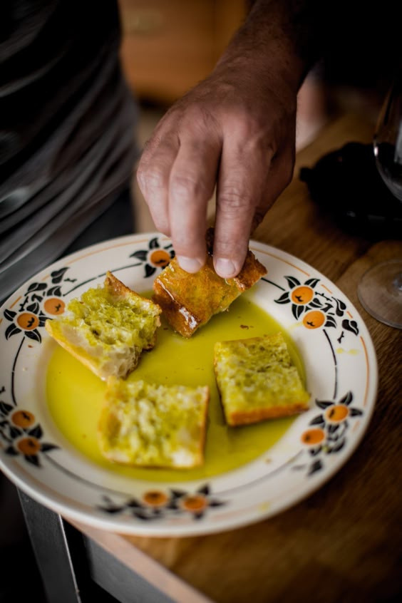 Mão mergulhando pão artesanal em azeite de oliva ALL-LIVA